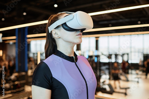 Side view portrait of young woman wearing VR gear in gym using technology in training copy space
