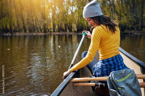 Woman, back and canoeing in nature on river, wellness hobby and backpack for supplies with paddle for rowing. Vacation, relax and explore exercise on travel holiday, canoe boat and trees on lake © peopleimages.com