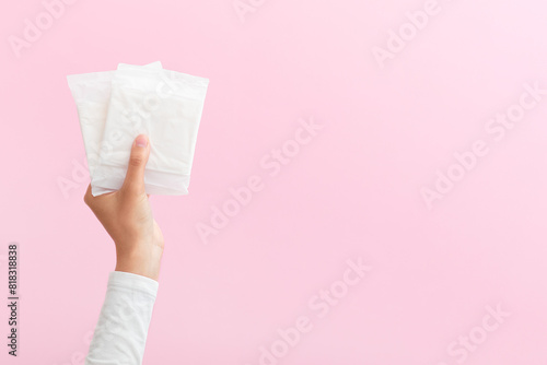 The girl is holding feminine sanitary pads in her hands. Pink background. Period. Top view. Space for text.