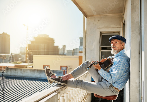Artist, senior and man with acoustic guitar for playing with retired musician on balcony in town for memories. Elderly, creative and proud of accomplishments with blues or folk song in urban Italy. photo