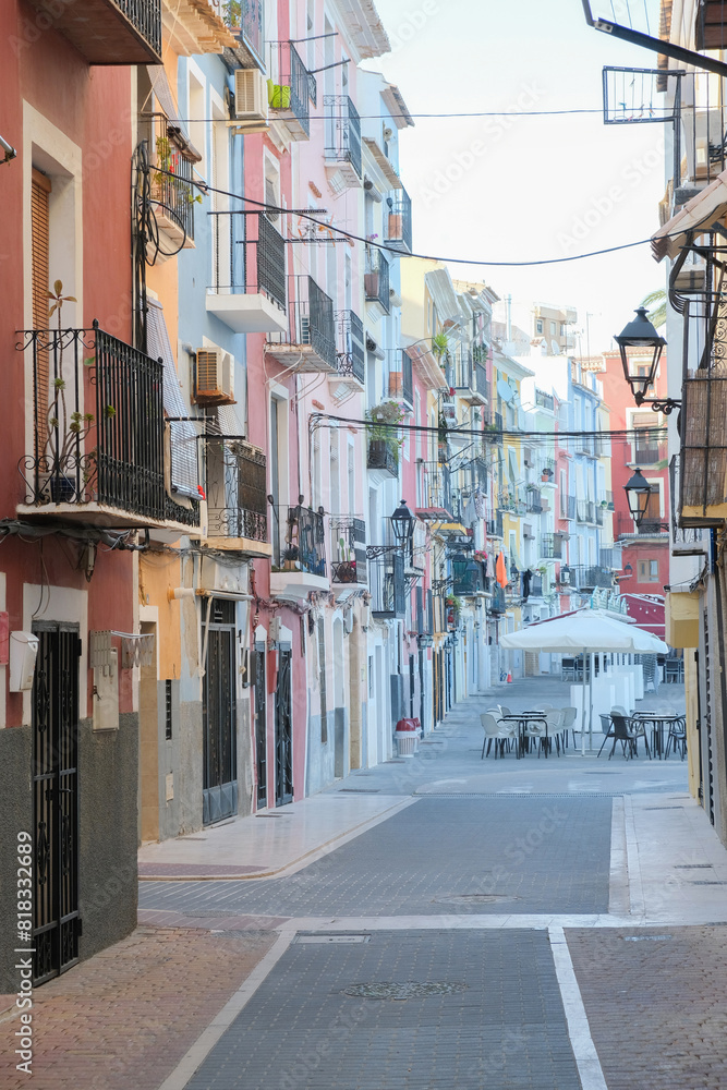 Obraz premium View to beautiful narrow Villajoyosa street with multi-colored houses. La Vila Joiosa - coastal town, Valencian Community, Spain, by Mediterranean sea