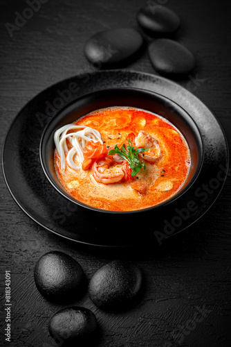Composition of tom yam soup with shrimp and noodles on black background. The Art of Japanese Cuisine. Food photography for menu and sushi bar decoration 