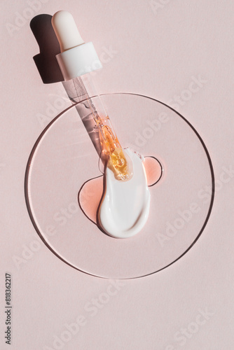 Serum dropper with cosmetic cream smear on pink