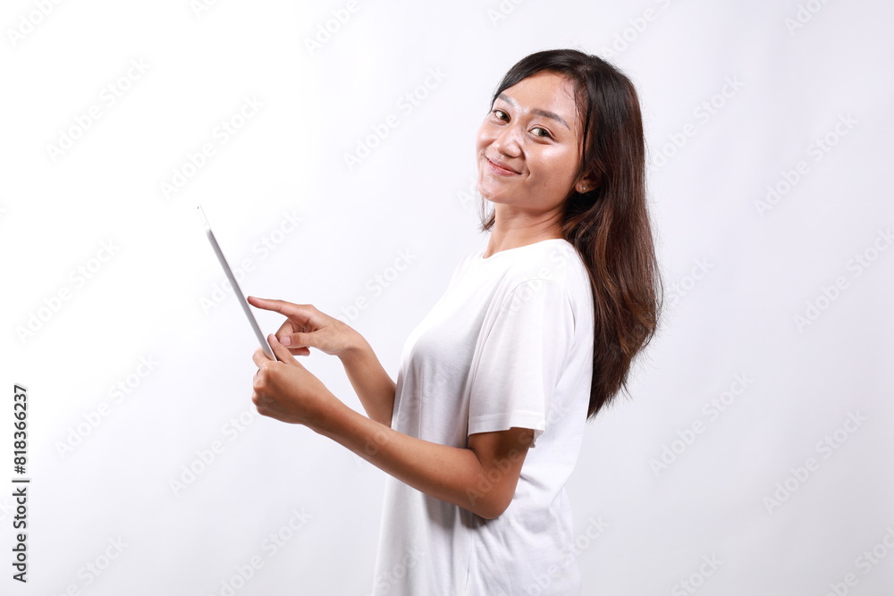 Attractive young asian woman holding a digital tablet while standing over white background looking at camera Attractive young asian woman holding a digital tablet while standing over white background looking at camera