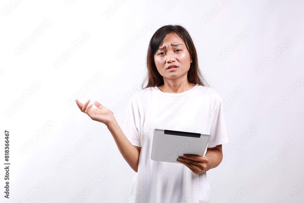 Young asian woman with holding tablet computer and looking directly at the camera with confused face expression Young asian woman with holding tablet computer and looking directly at the camera with confused face expression