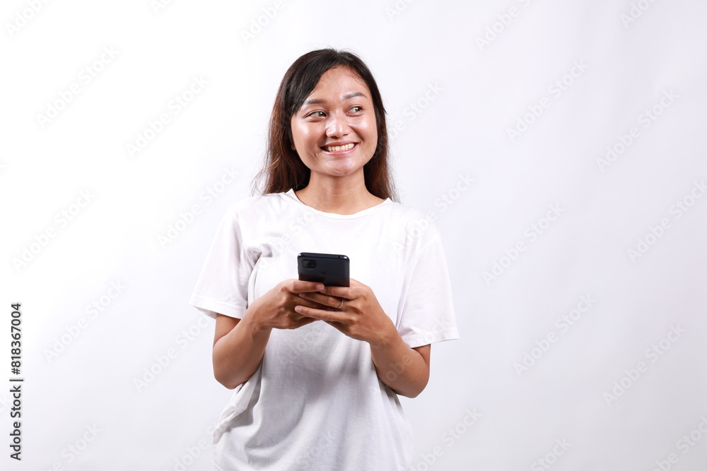 Smiling pleasant young asian woman standing using mobile phone while looking sideways. Isolated on white Smiling pleasant young asian woman standing using mobile phone while looking sideways. Isolated on white