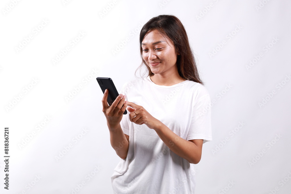 Beautiful smiling asian girl using mobile phone, looking at smartphone pleased. Isolated on white with copyspace
