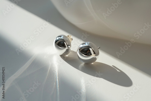 Contemporary silver earrings casting delicate shadows in natural sunlight  epitomizing minimalist elegance.