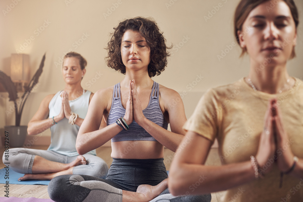 Meditation, group and women in yoga studio for calm mind, mindfulness and spiritual wellness with chakra balance. Pilates girls, health class and lotus pose for zen aura and prayer hands for healing