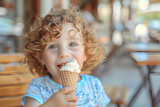 Kid eating ice cream in café. Funny curly child with ice-cream outdoor.