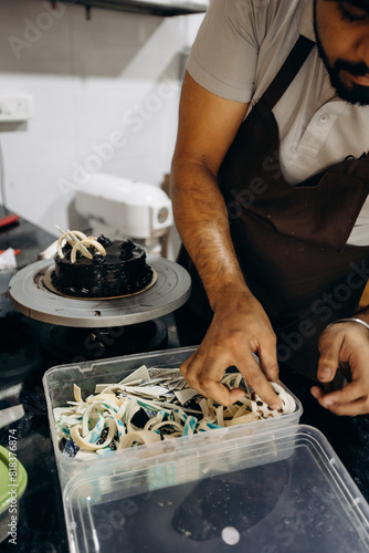 Making cakes to order. Unrecognizable male chef decorates candied chocolate cake in his kitchen. 