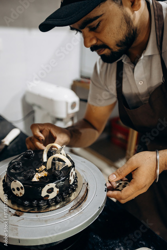 Small business and entrepreneurship. Professional male chef decorates candied chocolate cake .