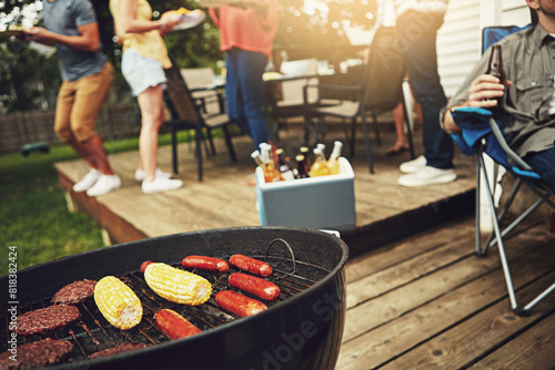 Food, barbecue and outside on weekend with grill for corn, sausage and cooking burgers in backyard. Friends, drinks and dinner party with reunion, meal and summer in America with alcohol for people. photo