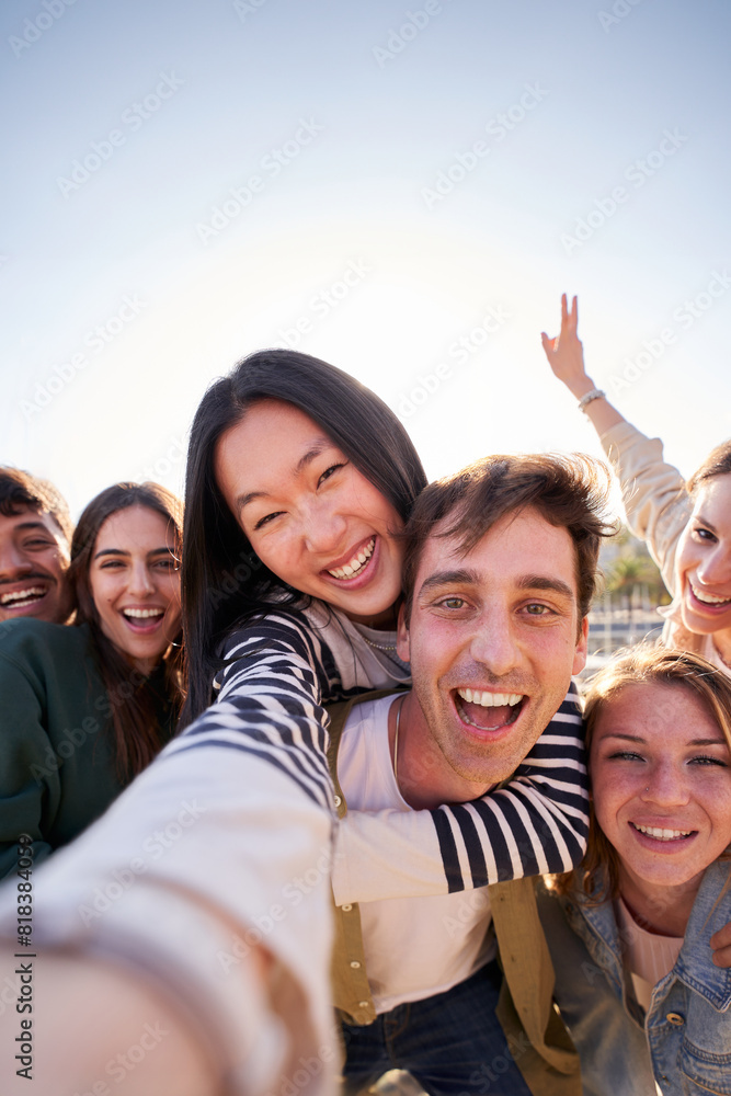 Vertical. Group of diverse happy young friends taking selfie together looking smiling at camera. Millennial people sharing cheerful community moments posing piggyback with peace gestures raised Vertical. Group of diverse happy young friends taking selfie together looking smiling at camera. Millennial people sharing cheerful community moments posing piggyback with peace gestures raised