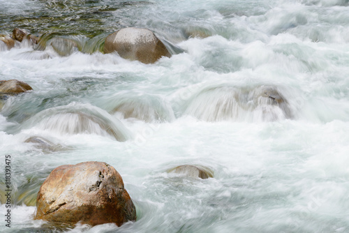 Turbulent clean river water crashes over smooth river rocks creating whitewater