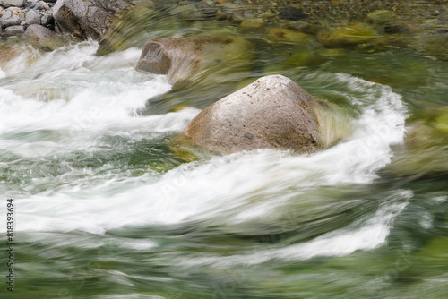 Clean fresh water stream flows in slow motion with silky lines around river rock © IanDewarPhotography