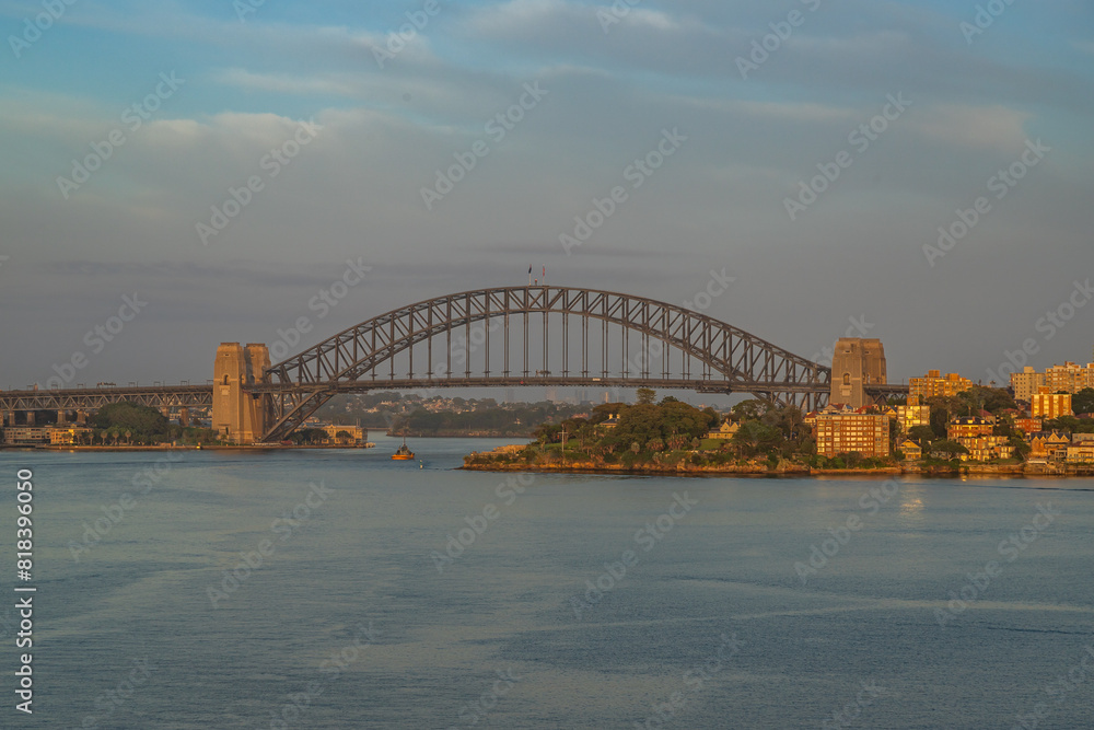 Fototapeta premium Extraordinary view of Sydney's Icons, namely the Sydney Opera House, Sydney Harbor Bridge and Sydney Downtown, while arriving by cruise ship in a beautiful sunrise.