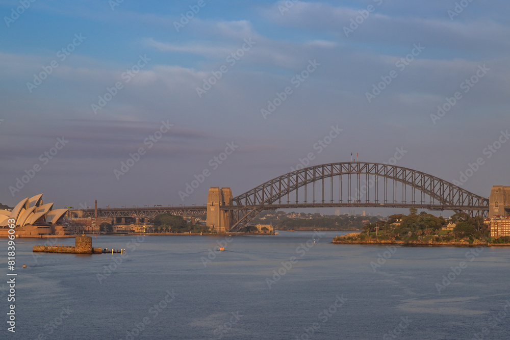 Obraz premium Extraordinary view of Sydney's Icons, namely the Sydney Opera House, Sydney Harbor Bridge and Sydney Downtown, while arriving by cruise ship in a beautiful sunrise.