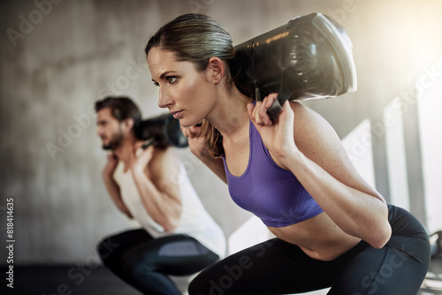 Squat, sandbag and fitness exercise or gym class with personal trainer for training, weights or strength. Man, woman and glutes routine for muscle building or leg goals together, equipment or workout