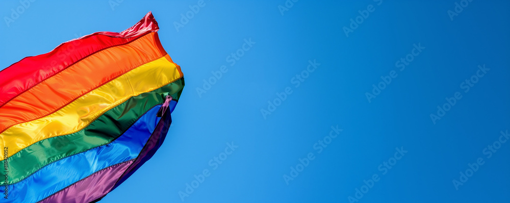 A vibrant rainbow flag waves against a clear blue sky, symbolizing LGBTQ pride and unity. A vibrant rainbow flag waves against a clear blue sky, symbolizing LGBTQ pride and unity.