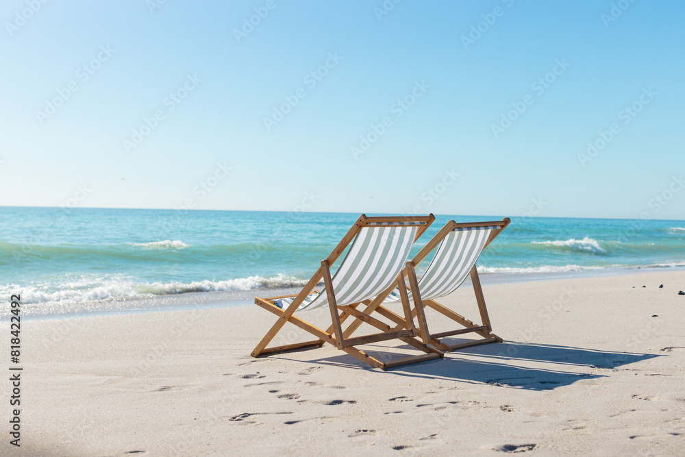 At beach, two empty chairs facing ocean, waiting for visitors At beach, two empty chairs facing ocean, waiting for visitors