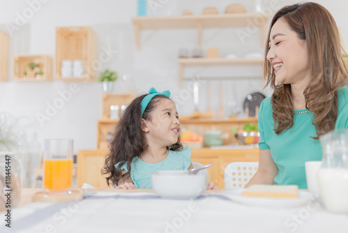 Asian children and her mom have a breakfast in the morning, child nutrition and development, they feeling happy in family time © jokekung