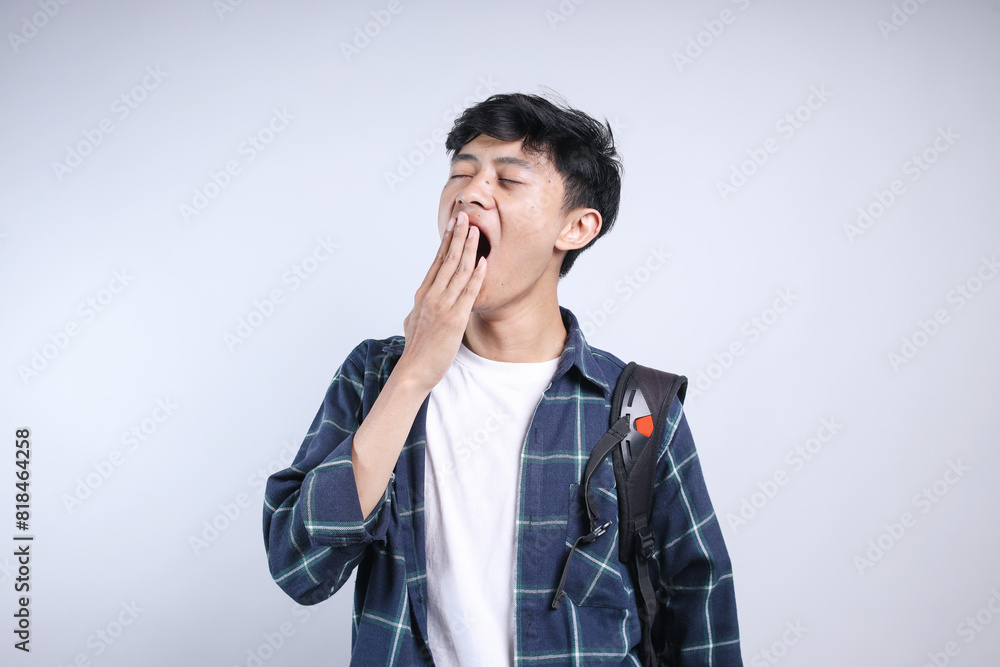 Potrait Of Young Asian College Student Man Yawning Covering Mouth With Hand Isolated On White Background Potrait Of Young Asian College Student Man Yawning Covering Mouth With Hand Isolated On White Background
