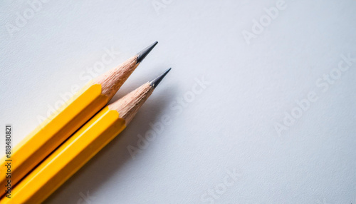 Two yellow pencils placed parallel on a white background with ample caption space on the side. Top view with copy space for text © Your Hand Please
