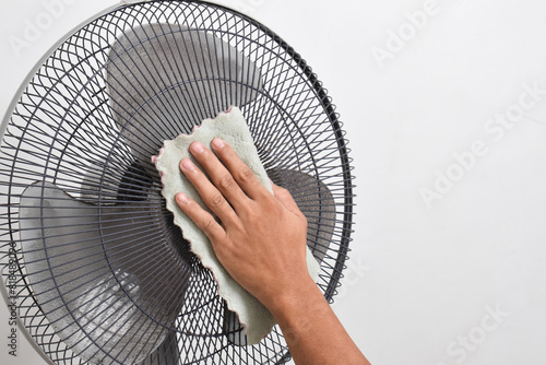 Close up hand holding a cloth to clean the dirty parts and dust on the fan. Clean dirty fan blades with a cloth. photo