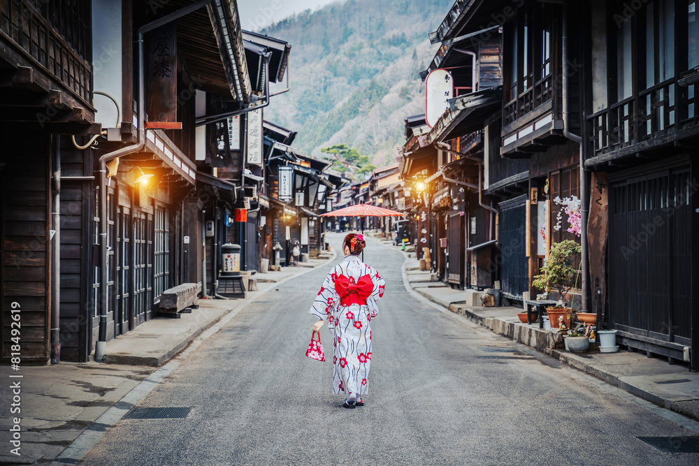 Obraz premium Asian woman wearing a traditional Japanese kimono holds an umbrella at Narai Juku in Nagano, Japan. Translation Narai Juku Village..