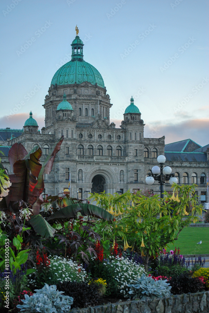 Fototapeta premium Victoria's legislature building shining with lights and blooming spring flowers