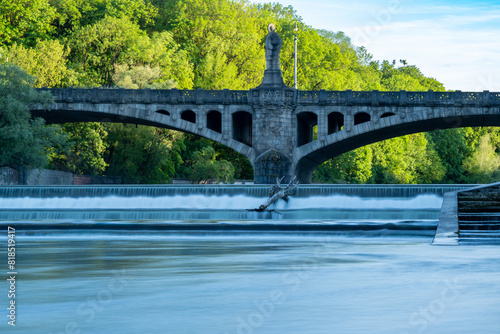 Maximiliansbrücke with statue Pallas Athene and large cascades with washed up tree trunk in the river Isar Munich Bavaria Germany photo