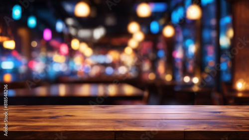 A wooden table in front of an out of focus bar with blue and purple lighting.