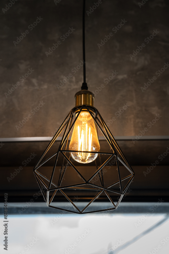 Classing ceiling lighting lamp with metal cage that glowing in warmlight shade. Interior decoration object equipment, Close-up and selective focus.
