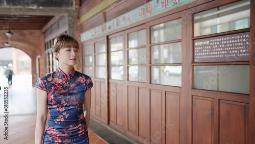 Young Taiwanese woman in blue floral cheongsam dress walking along arched colonnade in Bopiliao Old Street, Wanhua District, Taipei City. Slow-motion photo