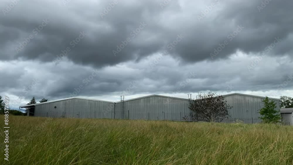 Cloud time lapse above factory, warehouse with grass and tree. Time flowing when working in job. The impact of industry on climate Cloud time lapse above factory, warehouse with grass and tree. Time flowing when working in job. The impact of industry on climate