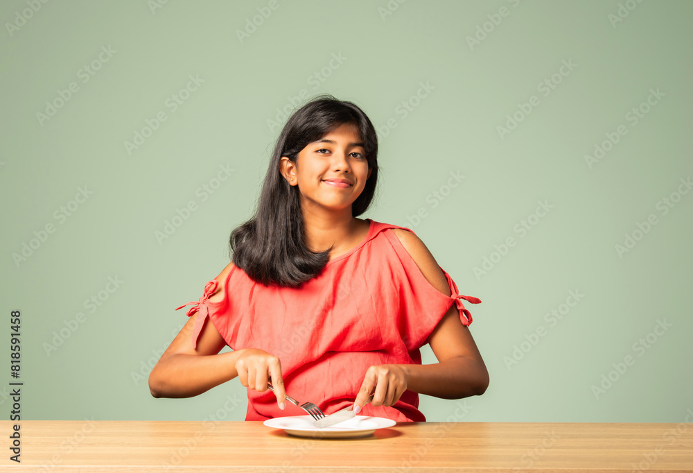 Asian Indian adorable girl child holding empty ceramic plate with happy expressions, sitting on table Asian Indian adorable girl child holding empty ceramic plate with happy expressions, sitting on table