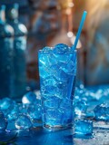 A glass of blue liquid with a straw in it is on a table with ice