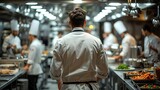 A top chef heading into the kitchen, viewed from behind, with the restaurant staff preparing for service,