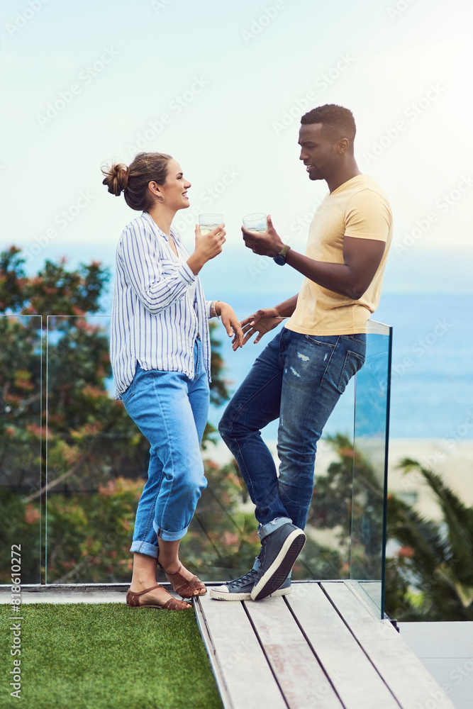 Couple, balcony and alcohol to relax in outdoor, bonding and together for love or laughing. People, terrace and speaking on holiday or vacation, juice and trees or ocean view for peace and calm