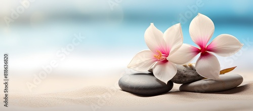 Close up image of spa stones with a flower on a sandy beach offering a beautiful and tranquil copy space image