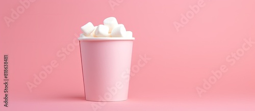 A marshmallow is placed in a paper cup against a pink background with room for additional images or text