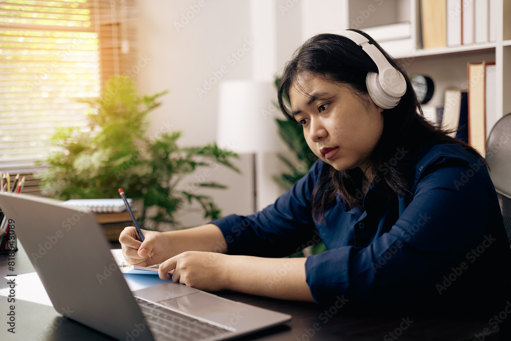 creative young student uses a laptop to complete online homework for college and university courses. Woman studies a book and conducts research for online academy using laptop in office. creative young student uses a laptop to complete online homework for college and university courses. Woman studies a book and conducts research for online academy using laptop in office.