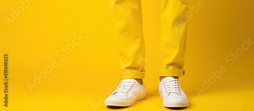 Fashionable white jeans and sneakers placed on a vibrant yellow background providing a captivating copy space image