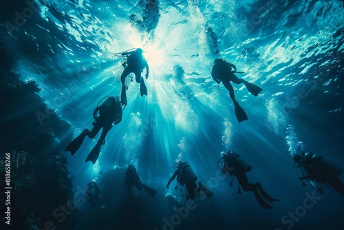 Silhouettes of scuba divers ascending towards the ocean surface