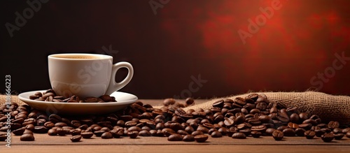 On the table there is a copy space image of a coffee cup accompanied by a pile of coffee beans