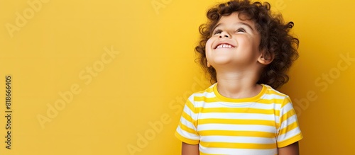 Copy space image A bright striped T shirt clad child emotionally emphasizes an idea through a gesture in a studio portrait against a yellow background photo