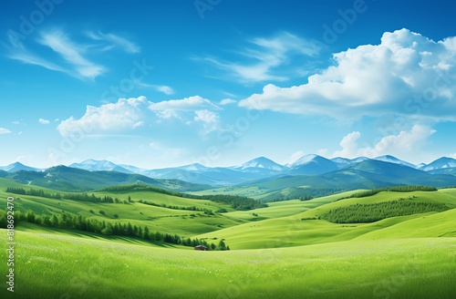 Green grassy hills with blue sky and mountains landscape background © Sunisa
