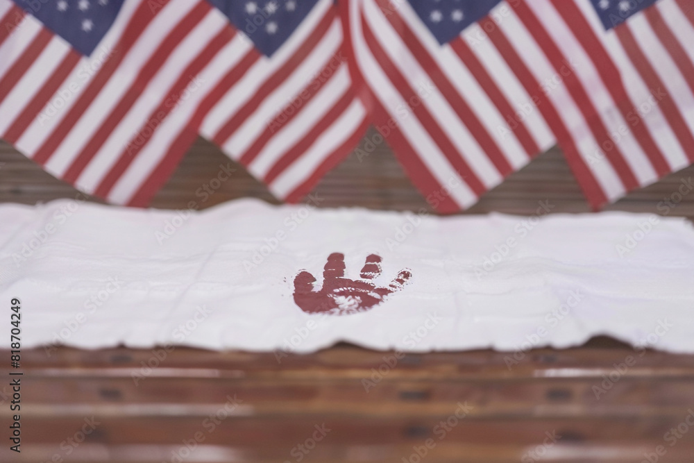 Fototapeta premium White banner features a child's handprint with American flags waving in the background for a creative and heartfelt Memorial Day tribute.