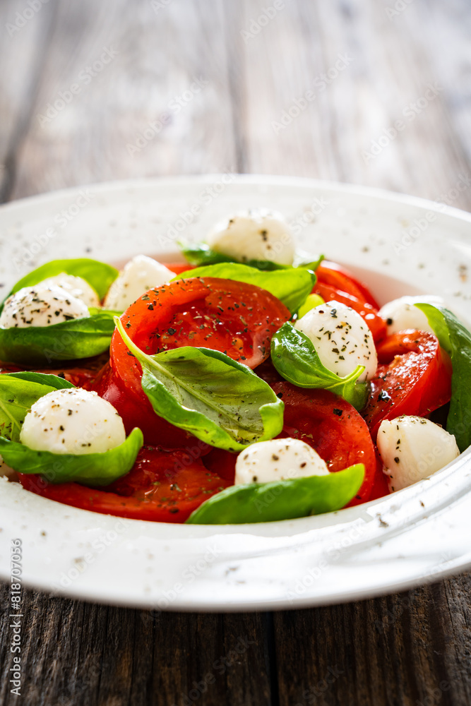Caprese salad - tomatoes and mozzarella balls served in white bowl on wooden background
Caprese salad - tomatoes and mozzarella balls served in white bowl on wooden background